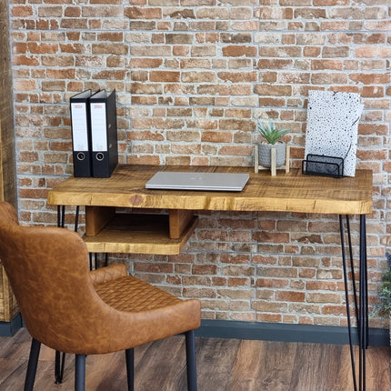 Wooden desk with office items against a brick wall